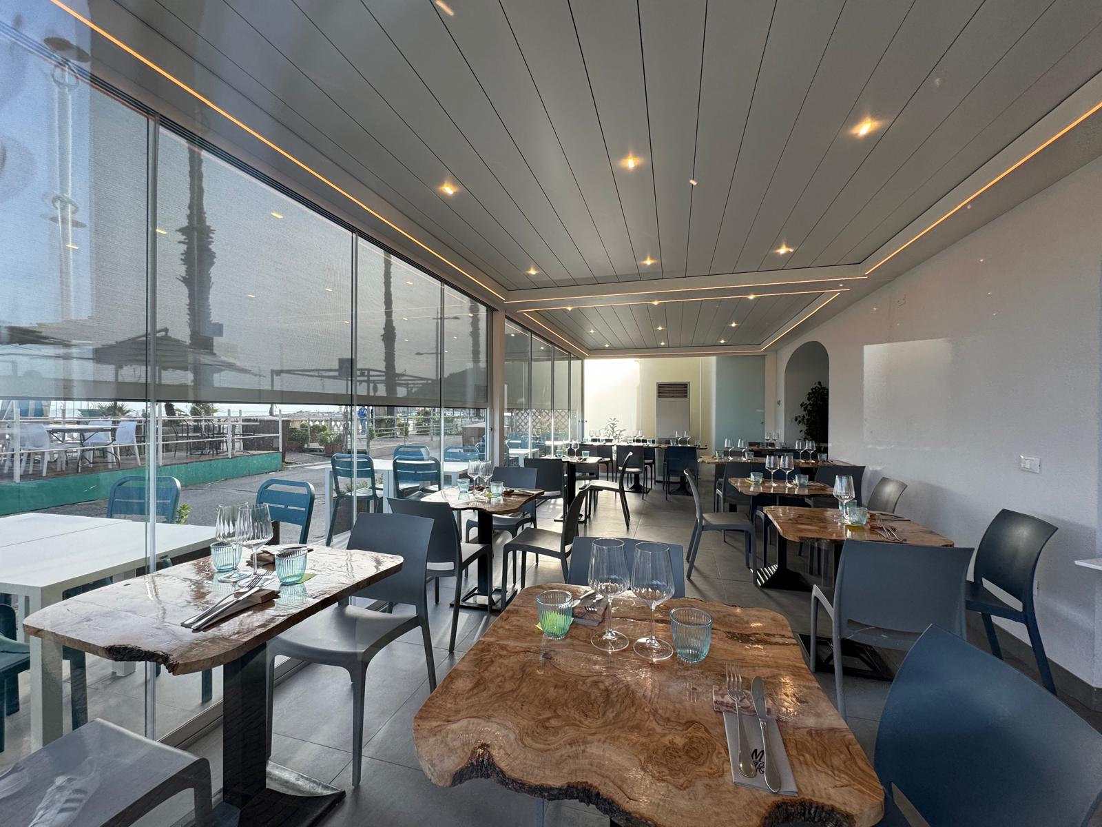 Pergola&nbsp; bioclimatica Brera a lame retraibili. Versione full optional con vetrate Slide Glass, faretti quadra light e tende verticali Raso filtranti.